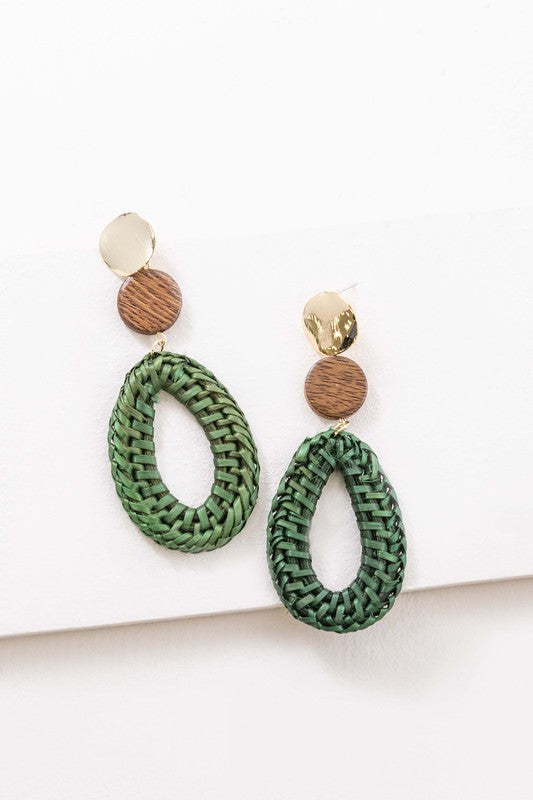 The Oval Wicker Drop Earrings exude tropical vibes with their green wicker design, complemented by round wooden and gold-toned accents, and feature a sterling silver post set against a white background.