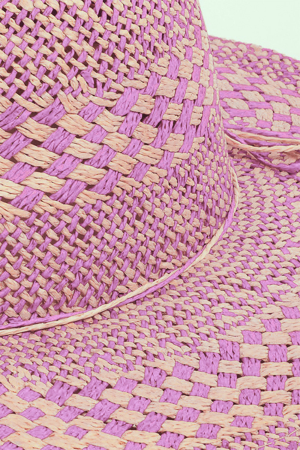 The Fame Checkered Straw Weave Sun Hat, featuring a sophisticated pink and purple checkered design, is elegantly displayed on a white background, highlighting its wide brim.