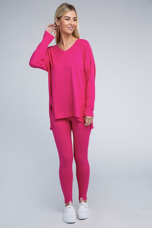 Clad in the Brushed DTY Microfiber Loungewear Set, a person stands against a plain background, showcasing its buttery soft, bright pink long-sleeve top and matching leggings, complemented by white sneakers.