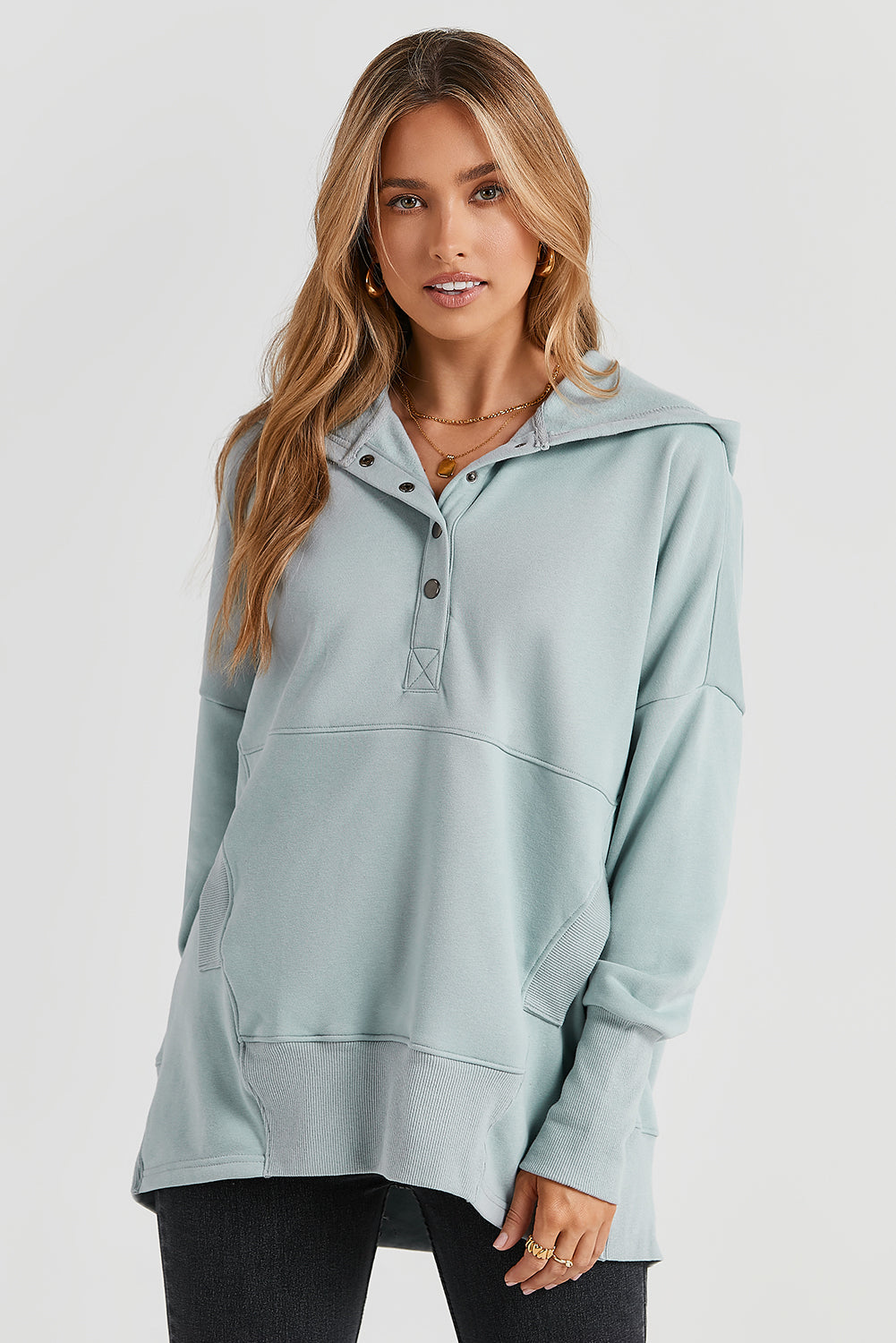 A person with long hair is smiling and looking over their shoulder while wearing a Gray Batwing Sleeve Pocketed Henley Hoodie.