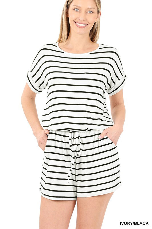 A person is smiling while wearing the Stripe Romper with Pockets, featuring a chic design and an elastic waist, with hands casually placed in the pockets.