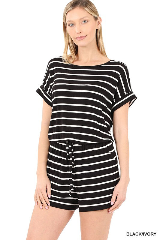 A person is smiling while wearing the Stripe Romper with Pockets, featuring a chic design and an elastic waist, with hands casually placed in the pockets.