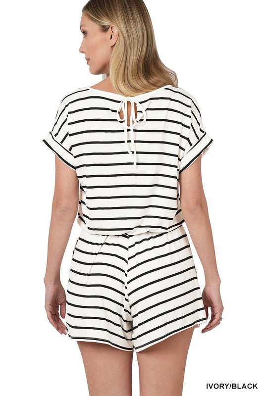 A person is smiling while wearing the Stripe Romper with Pockets, featuring a chic design and an elastic waist, with hands casually placed in the pockets.