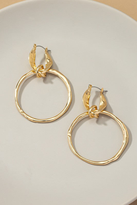 The product, "Statement hammered hoop drop earrings," showcases large, gold-plated hoops with textured surfaces, elegantly displayed on a white background.