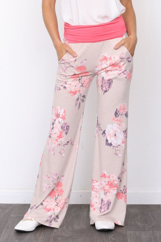 A person wearing the Vintage Floral Wide Leg Pants with a pink waistband and a white top, standing on a wooden floor.