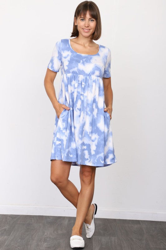 A person in a stylish Cloud Tie Dye Midi Dress made from smooth polyester, paired with black sandals, stands on a light-colored floor in front of a beige curtain backdrop.