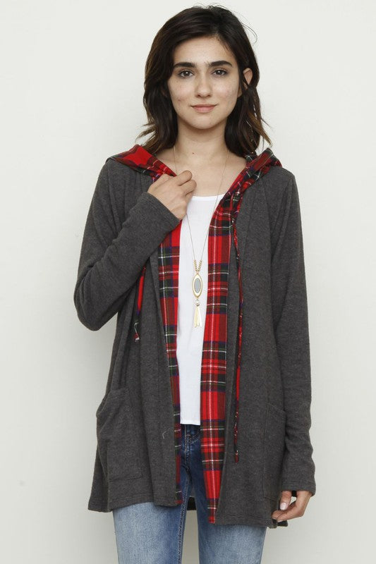 A person wearing a Plus Hooded Plaid Trimmed Cardigan, proudly made in the USA, pairs it with a white shirt and jeans, standing against a plain background.