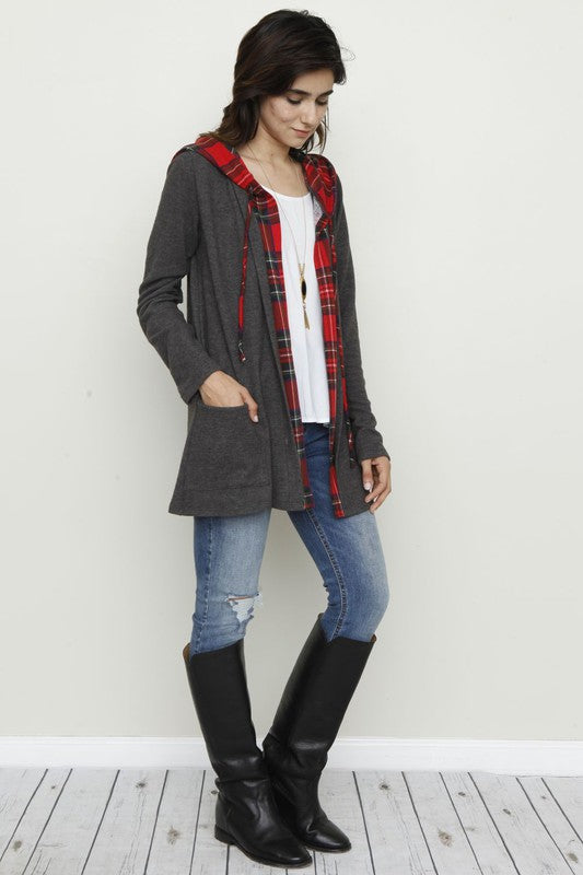 A person wearing a Plus Hooded Plaid Trimmed Cardigan, proudly made in the USA, pairs it with a white shirt and jeans, standing against a plain background.