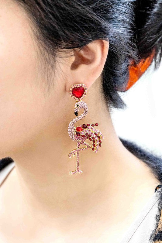 The Pink Flamingo Drop Earrings, featuring pink rhinestones and heart-shaped red studs with jeweled accents, add a charming flair of summer style against a white background.