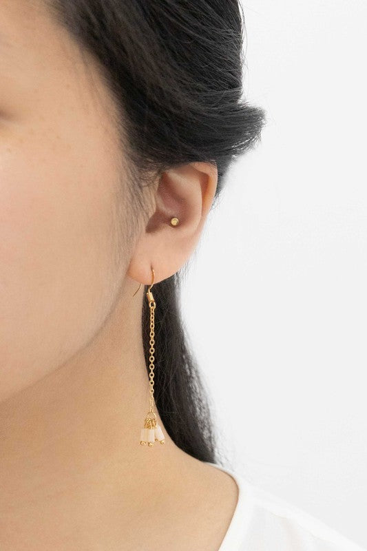 The Palm Dangle Earrings, featuring gold hooks with dangling chains and geometric designs, exude a touch of brass jewelry elegance.