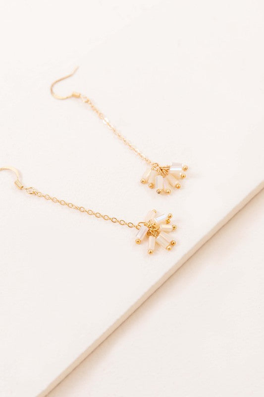 The Palm Dangle Earrings, featuring gold hooks with dangling chains and geometric designs, exude a touch of brass jewelry elegance.