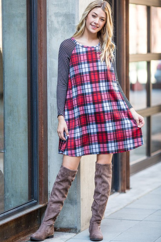 A person stands against a brick wall in a Stripe Sleeve A-Line Mini Dress with black and orange plaid, paired with an orange hat, smiling.