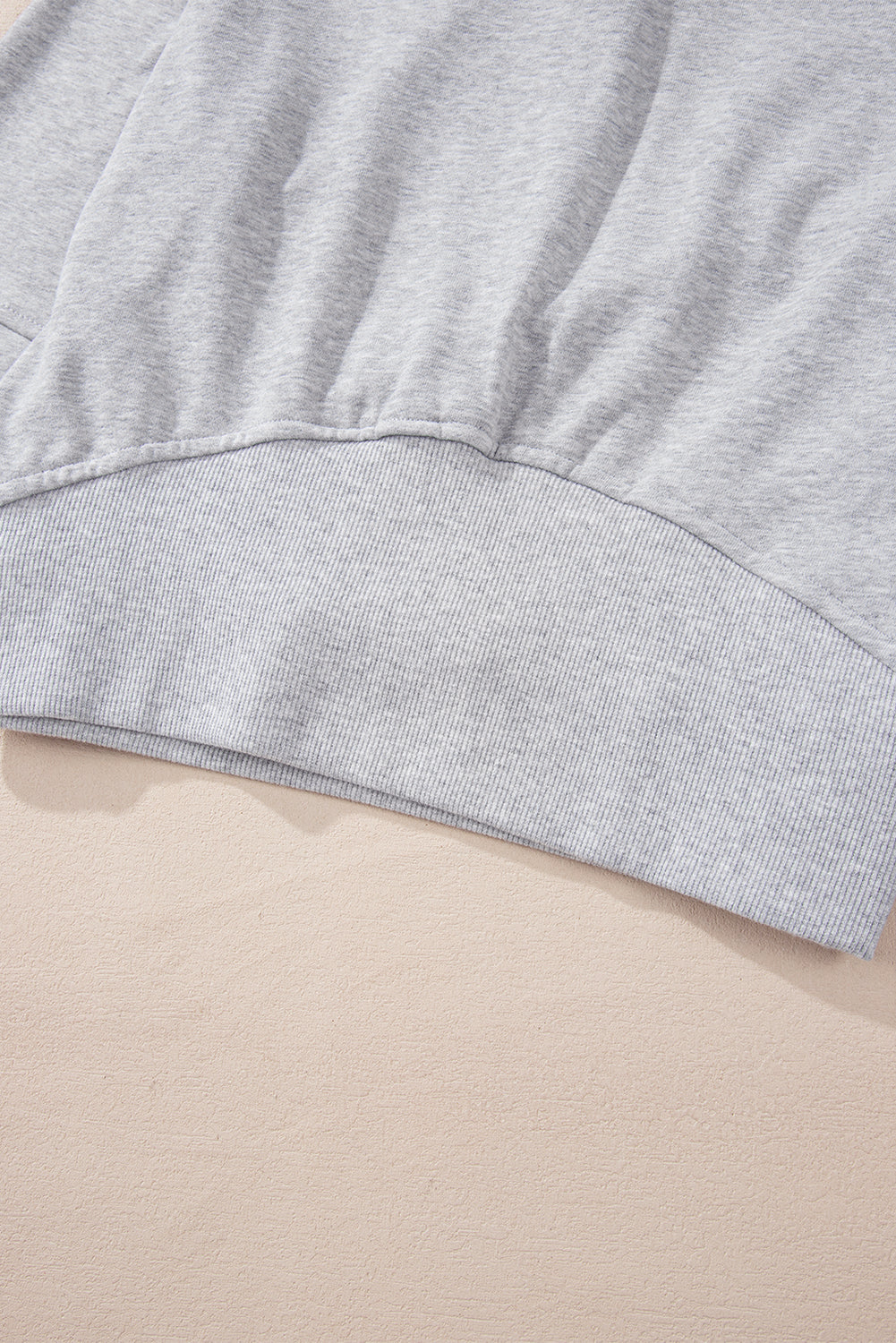 A woman with long, dark hair stands sideways, wearing a Light Grey Quarter Zip Stand Neck Kangaroo Pocket Sweatshirt that is perfect for layering, along with black shorts. She looks at the camera against a plain background, making this outfit ideal for casual occasions.