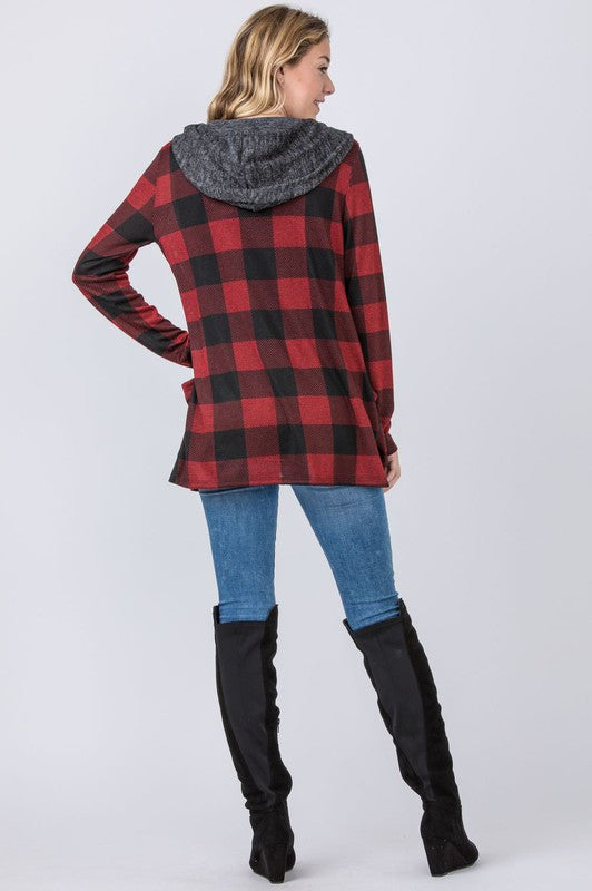 A person stands against a plain background, wearing the Plus Plaid Checker Print Cardigan with Hoodie in red and black, complemented by a gray hood and black shirt.