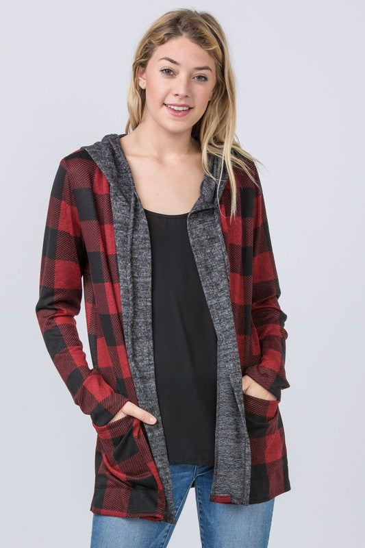 A woman wearing a Buffalo Plaid Hooded Cardigan and patterned pants stands against a white paneled background. Made in the United States.