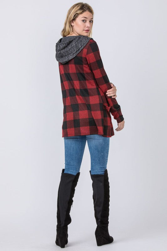 A person stands against a plain background, wearing the Plus Plaid Checker Print Cardigan with Hoodie in red and black, complemented by a gray hood and black shirt.