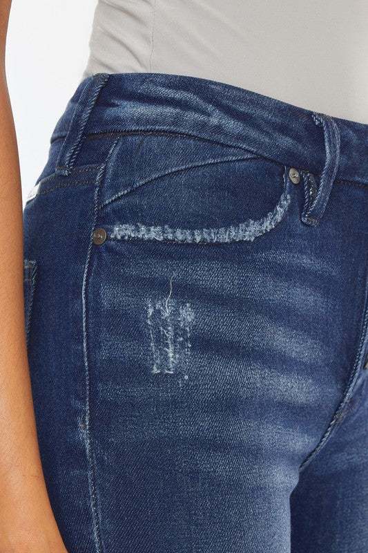 A woman in a gray tank top and High Rise Piecing Detail Super Skinny Jeans stands against a plain white backdrop while looking down and smiling. She is wearing black heeled sandals.