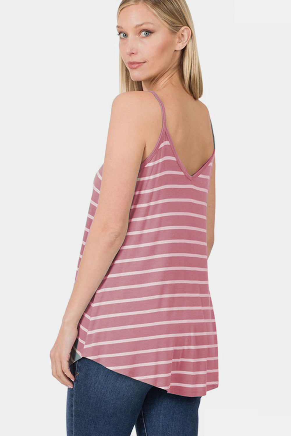 A person with curly hair wearing a chic Zenana Striped Curved Hem Cami in pink and white stands against a plain background, making it perfect for any summer wardrobe.