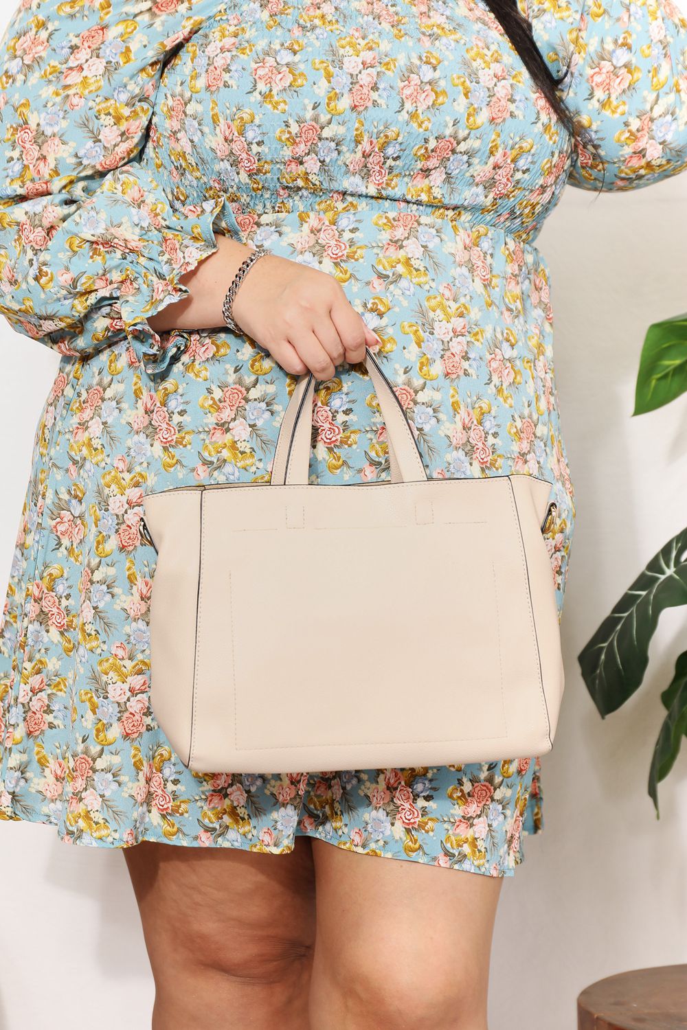 Person wearing a floral dress holds the SHOMICO Medium PU Leather Handbag with both hands.