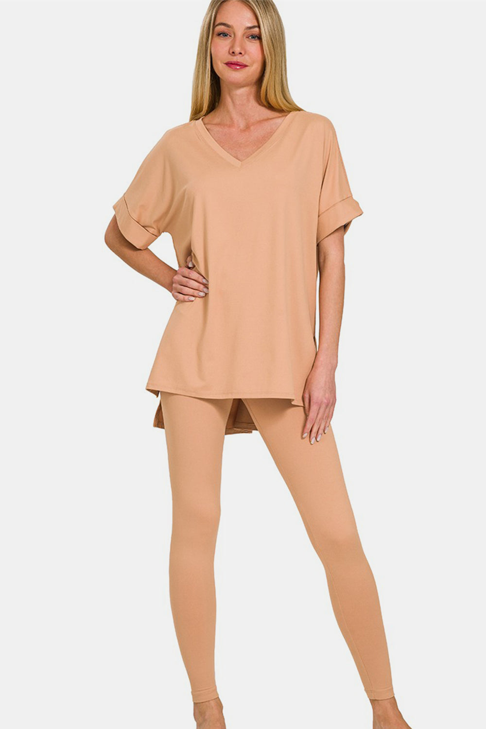 Against a simple backdrop, someone wears the Zenana Full Size V-Neck Rolled Short Sleeve T-Shirt and Leggings Lounge Set, seamlessly blending comfort and style with its chic beige ensemble.