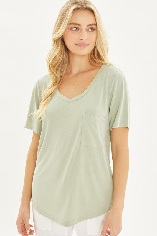 A woman with long blonde hair stands against a plain background, wearing the Knit Solid Jersey Basic V-Neck T-Shirt in light green and white pants.