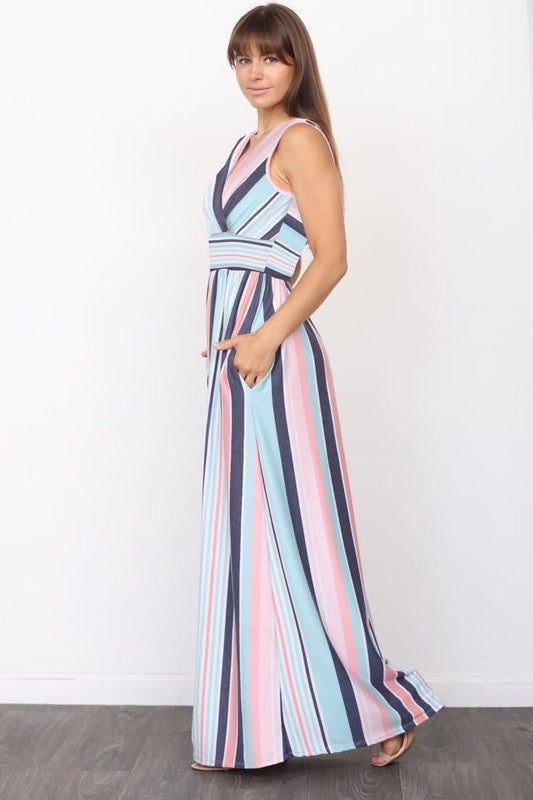 A person wearing a sleeveless, floor-length Surplice Stripe Maxi Dress with vertical yellow, blue, gray, and white stripes stands against a plain background.