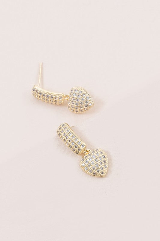 A pair of Amour Drop Earrings with pave set crystals on a light background, featuring 14k gold plating.
