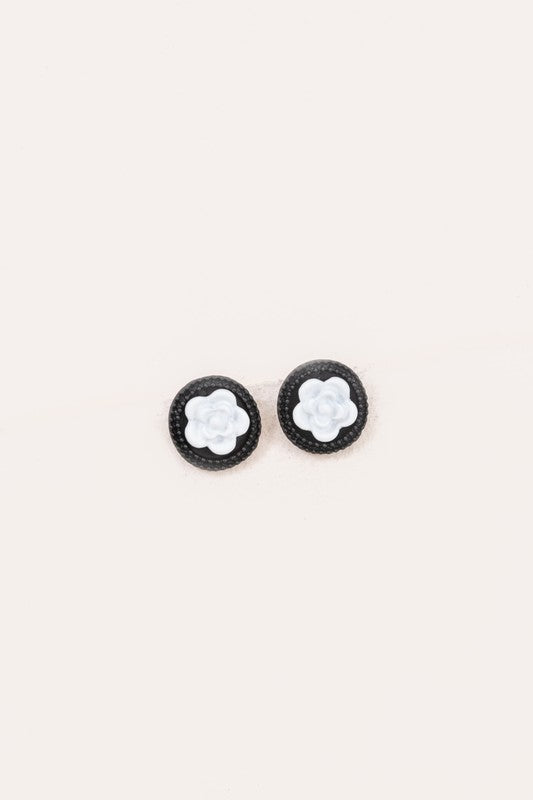 A pair of Noir Rose Stud Earrings with a black border and a white floral design in the center, crafted from Sterling Silver.
