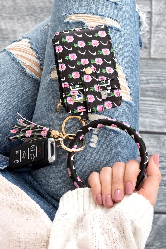 A person's hand holding a Key Ring Wallet Bracelet ID Zip Up with a leopard print design; cash and cards are partially visible inside the wallet, which features a hidden zipper pocket.