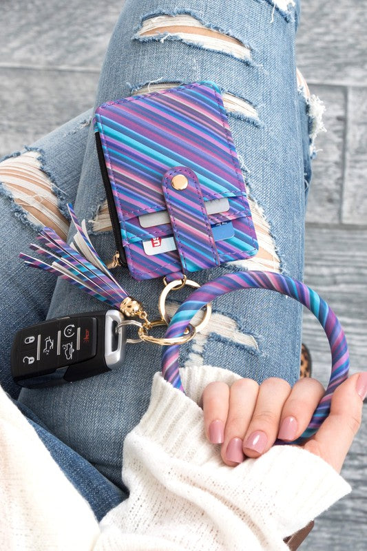A person's hand holding a Key Ring Wallet Bracelet ID Zip Up with a leopard print design; cash and cards are partially visible inside the wallet, which features a hidden zipper pocket.