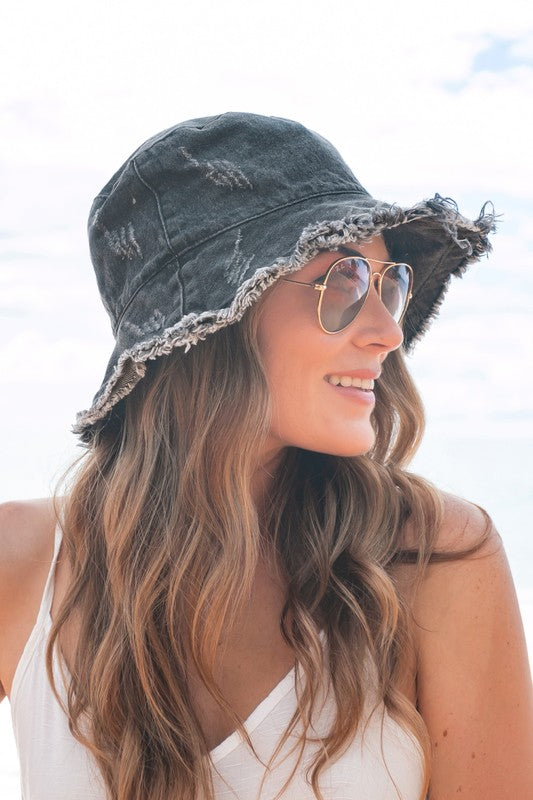 Woman wearing sunglasses and a Levi's Denim Bucket Hat with a frayed edge at the beach.