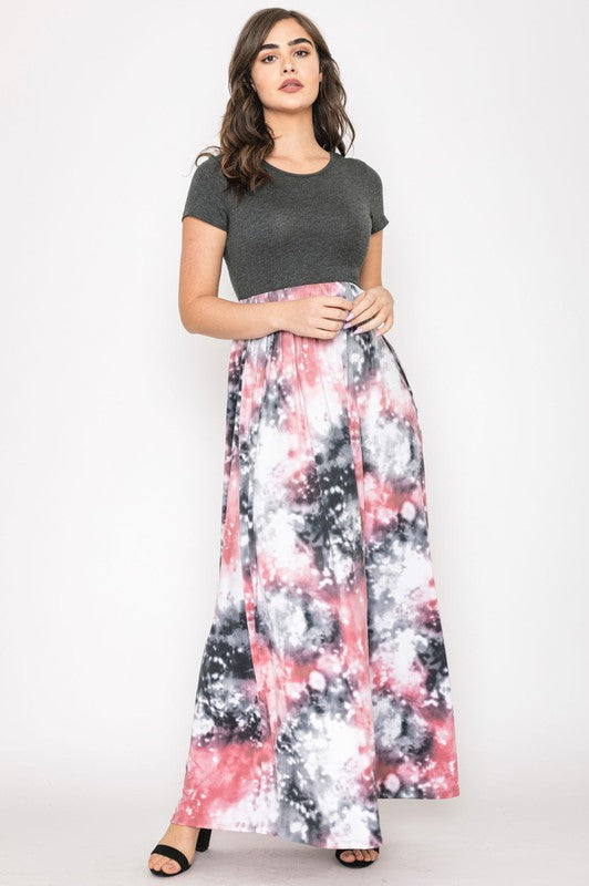 A woman in a gray top stylishly pairs her vibrant Two Tone Tie Dye Maxi Dress, standing against a plain background.