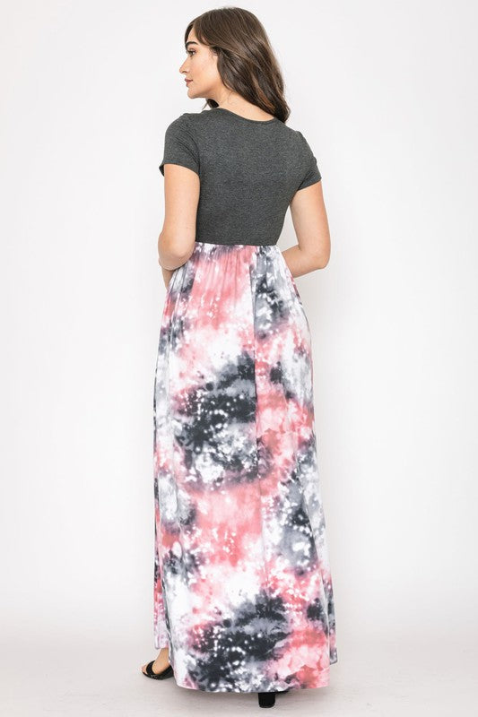 A woman in a gray top stylishly pairs her vibrant Two Tone Tie Dye Maxi Dress, standing against a plain background.