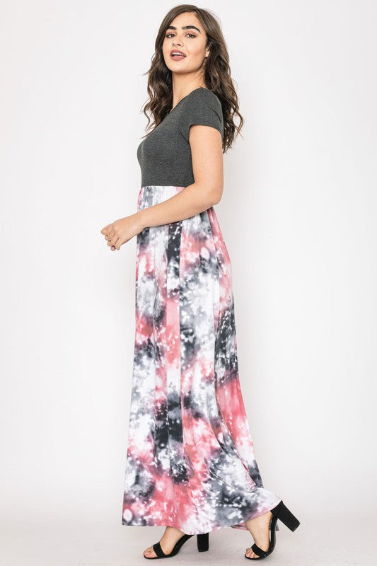 A woman in a gray top stylishly pairs her vibrant Two Tone Tie Dye Maxi Dress, standing against a plain background.