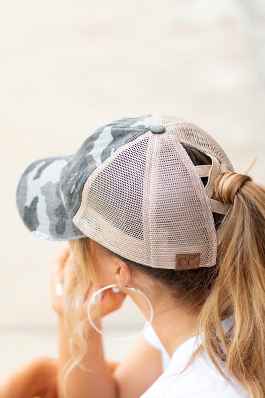 Woman wearing a black mesh CC Camo Criss-Cross Ponytail Cap with an adjustable velcro closure.