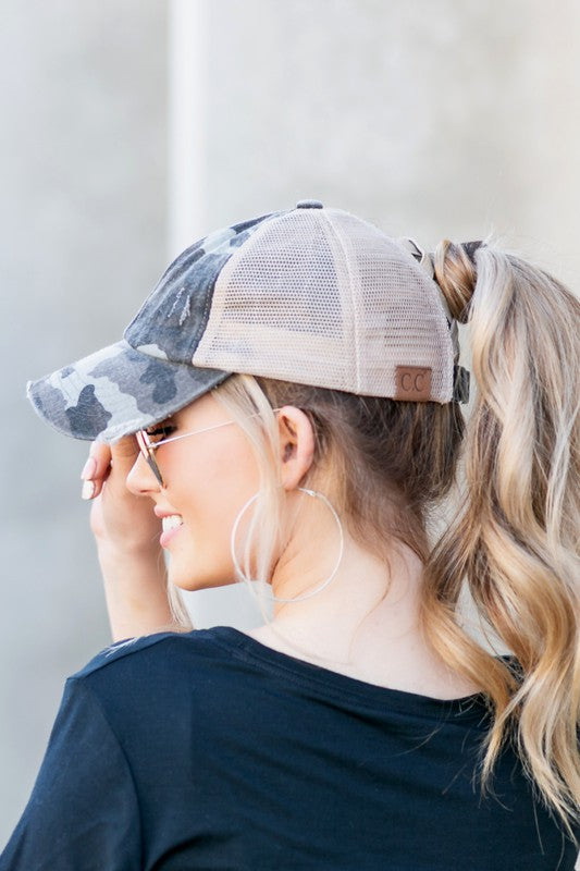 Woman wearing a black mesh CC Camo Criss-Cross Ponytail Cap with an adjustable velcro closure.
