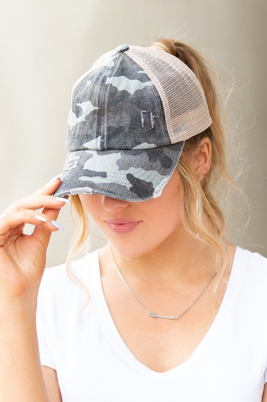 Woman wearing a black mesh CC Camo Criss-Cross Ponytail Cap with an adjustable velcro closure.