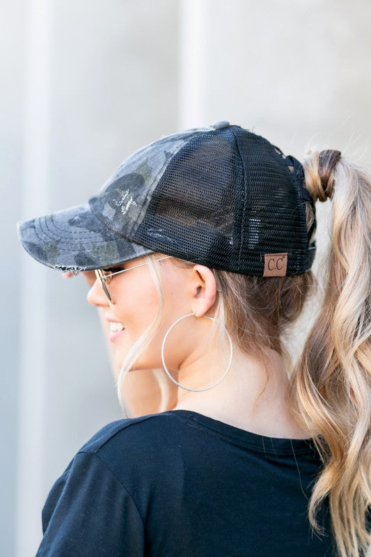 Woman wearing a black mesh CC Camo Criss-Cross Ponytail Cap with an adjustable velcro closure.