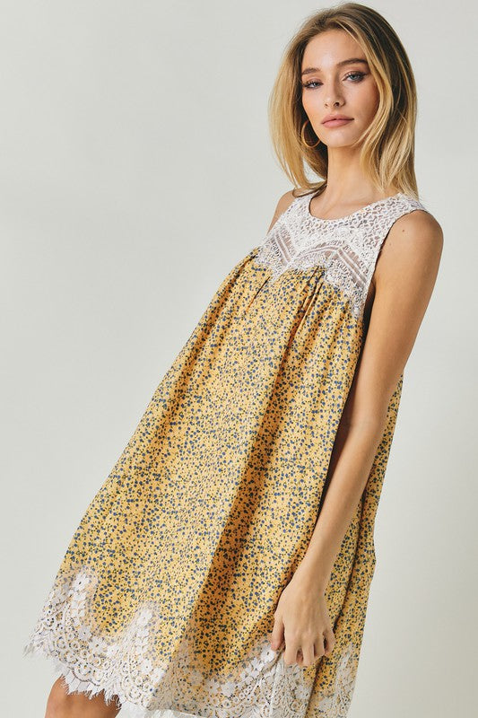 A woman wearing the Printed Sleeveless Lace Trim Mini Dress is seated against a light background.