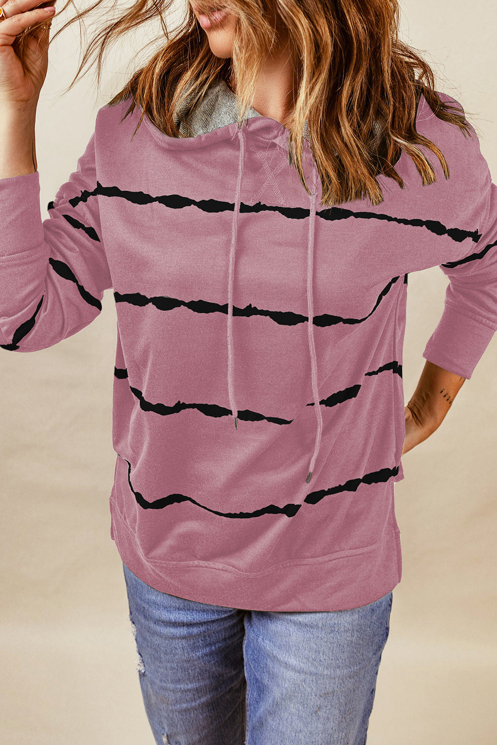 A person with wavy, light brown hair is wearing a Pink Tie-dye Striped Drawstring Hoodie with Side Split Tops and blue jeans, viewed from the back. The relaxed silhouette of the hoodie adds to its casual appeal.