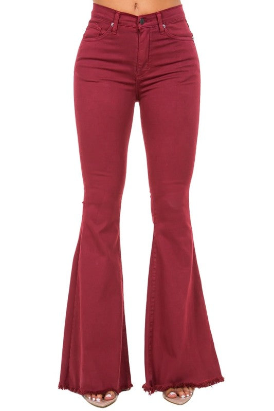 A person wearing high-rise, wine-colored Bell Bottom Jeans with frayed hems (Inseam 32), paired with open-toe shoes.