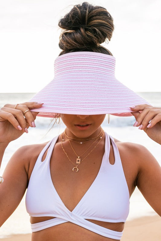 A woman from behind wearing a white bikini and a wide-brimmed, breathable Foldable Bow Stripe Visor on the beach.