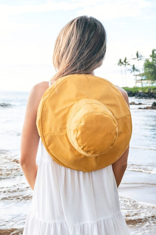 Smiling woman wearing sunglasses and a Drawstring Cargo Hat on a beach.