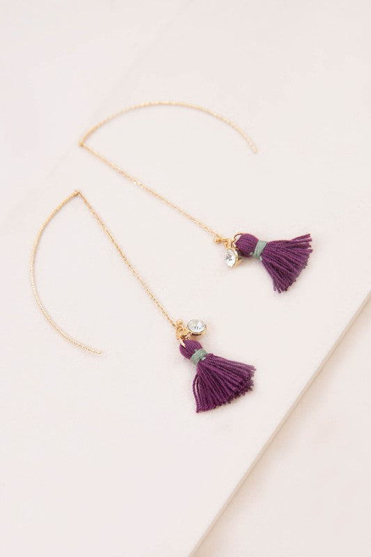 The Keely Tassel Threader Earrings, showcasing vibrant purple tassels and small crystal accents, are displayed on a light background, making them perfect for adding a touch of casual style to any outfit.