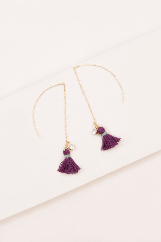 The Keely Tassel Threader Earrings, showcasing vibrant purple tassels and small crystal accents, are displayed on a light background, making them perfect for adding a touch of casual style to any outfit.