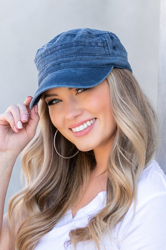 Woman in a white t-shirt and military-inspired black Distressed Cadet Hat Cap with an adjustable clasp, smiling at the camera.