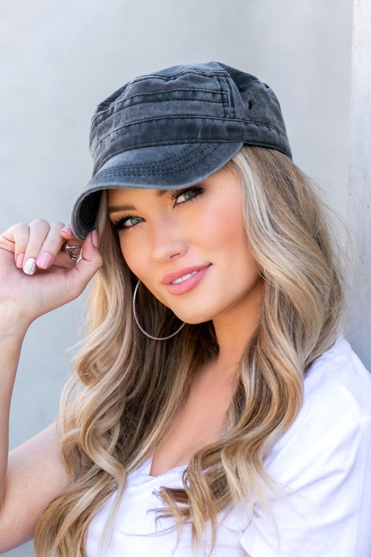 Woman in a white t-shirt and military-inspired black Distressed Cadet Hat Cap with an adjustable clasp, smiling at the camera.