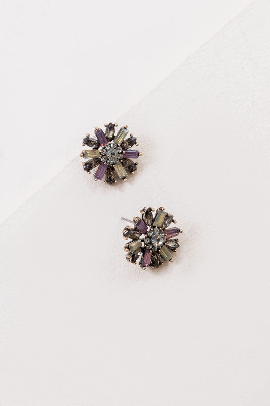 The Liesel Stud Earrings feature a floral design with vibrant purple and gray stones on a light background.