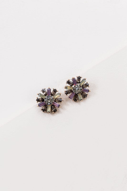 The Liesel Stud Earrings feature a floral design with vibrant purple and gray stones on a light background.