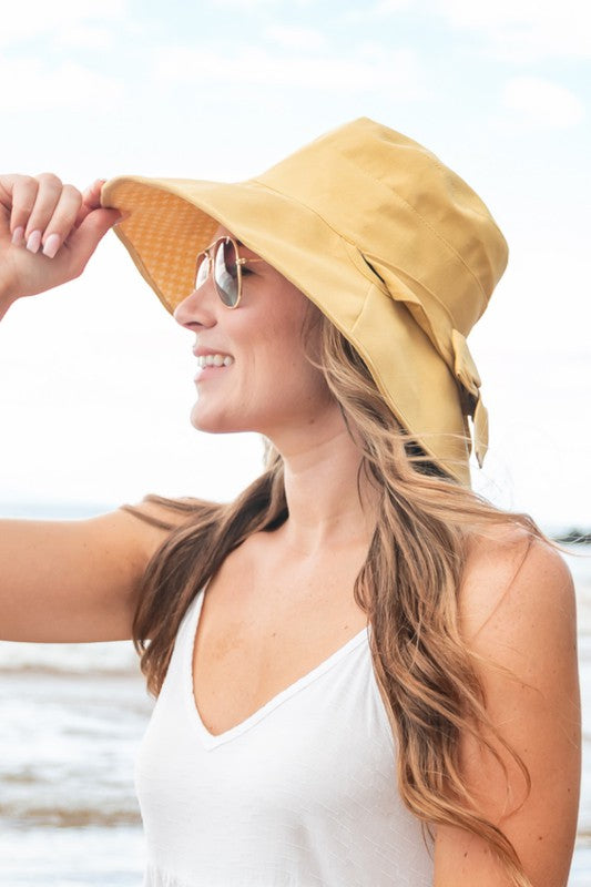 Woman wearing a wide-brimmed Bow Accent Cargo Hat at the beach.